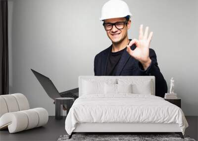 Portrait of an engineer with okay sign using a laptop isolated on white background Wall mural